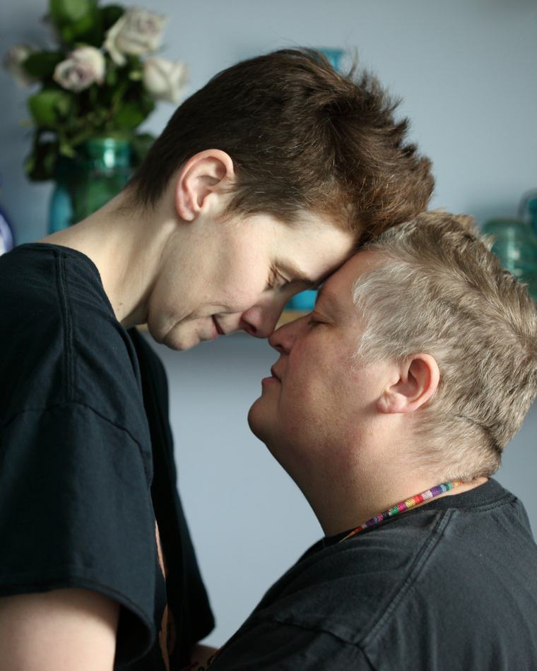 Two women standing close together at home, foreheads almost touching