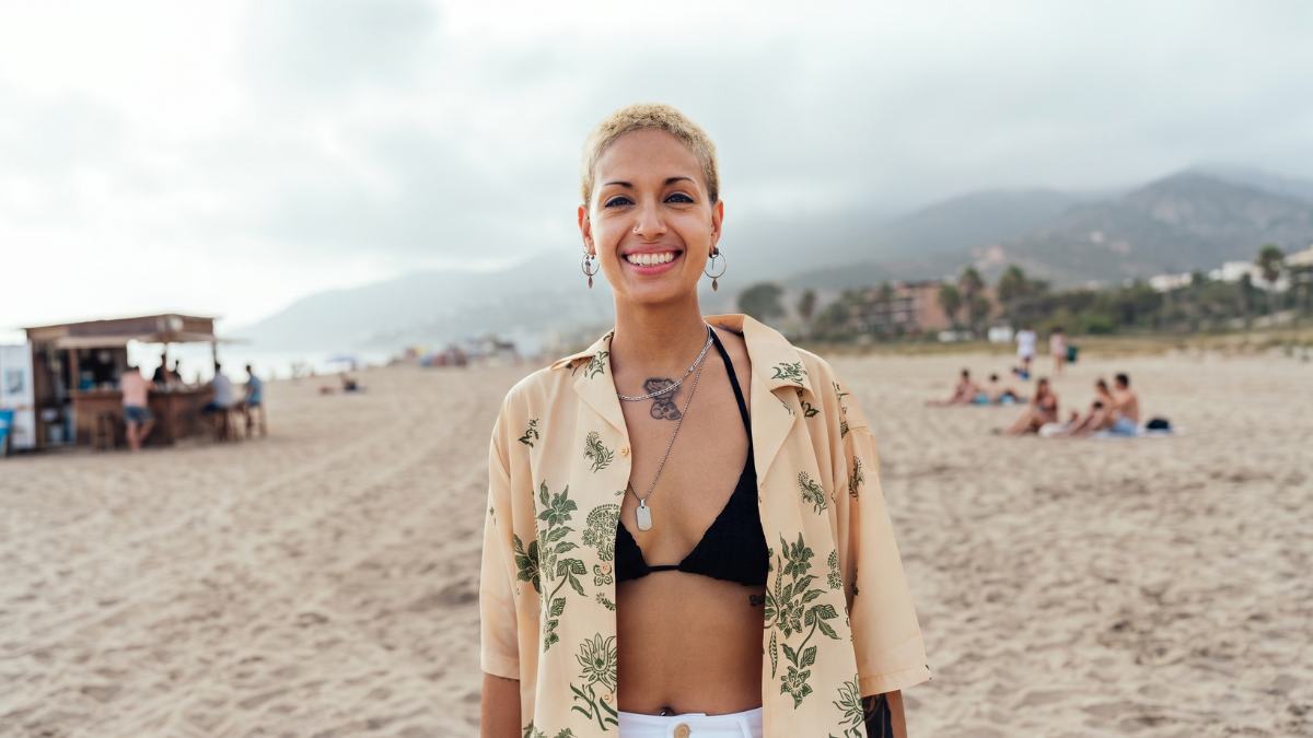 A woman on a sunny beach, smiling towards the camera